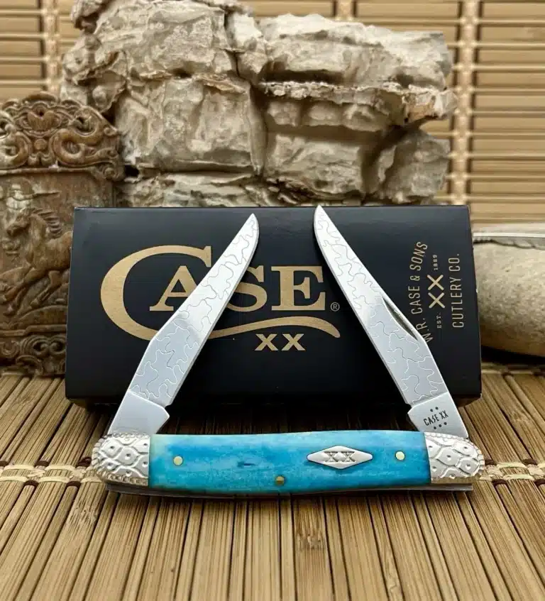 Case XX Muskrat with a Caribbean blue bone handle, etched blades and engraved nickel silver bolsters, shown open in front of its Case box